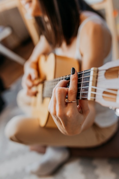 Junge Frau spielt weiße Gitarre. Frau, die Musik in weißen Kopfhörern hört.