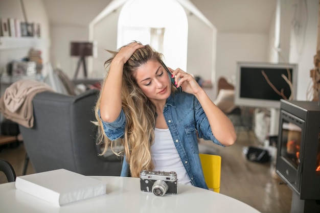 Foto junge frau spricht zu hause am tisch am handy