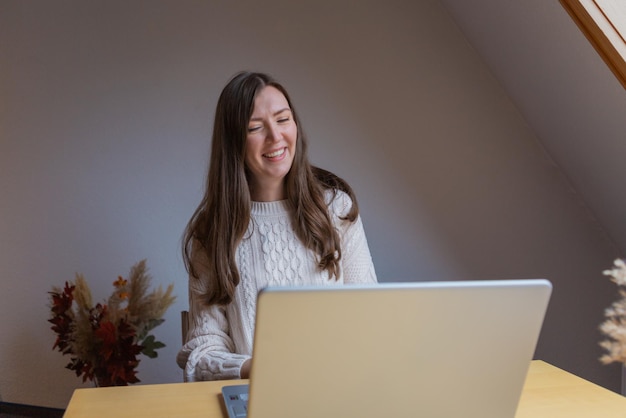 Junge Frau spricht zu Hause mit dem Laptop