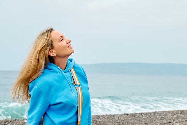 Foto junge frau steht am strand vor klarem himmel