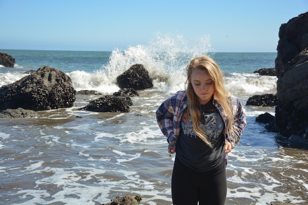 Foto junge frau steht am strand