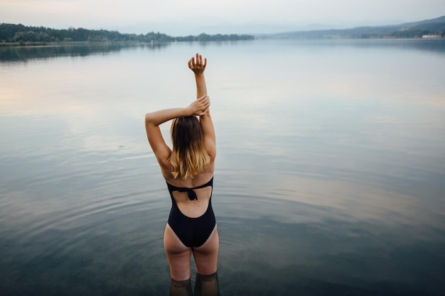 Junge Frau steht im Fluss gegen den Himmel