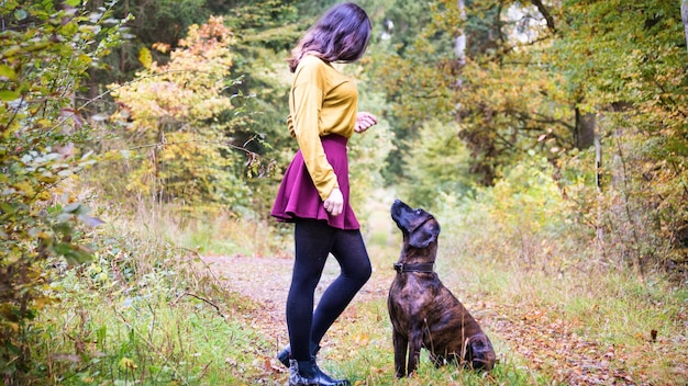 Junge Frau steht neben dem Hund auf dem Feld