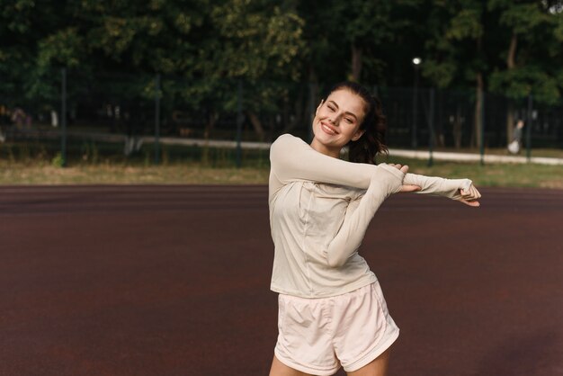 Junge Frau streckt ihre Arme beim Sport im Stadion aus