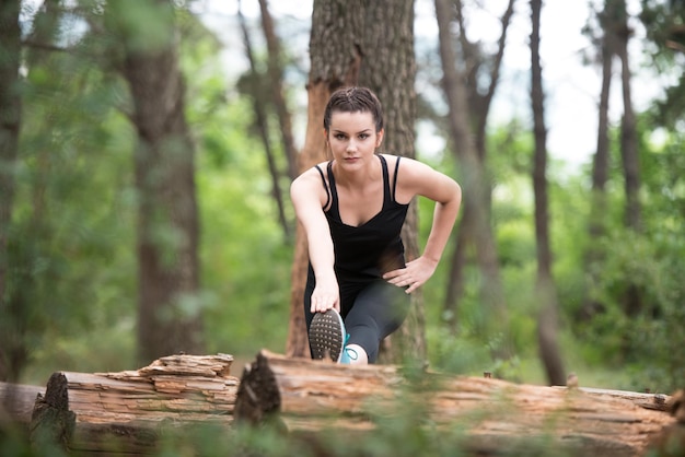 Junge Frau Stretching vor dem Laufen in bewaldeten Waldgebiet Training und Training für Trail Run Marathon Ausdauer Fitness gesunden Lebensstil Konzept