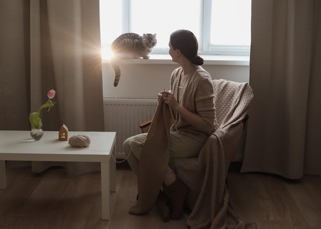 Junge Frau strickt in einem gemütlichen Zimmer zu Hause