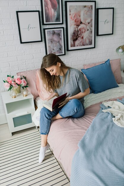 Junge Frau studiert zu Hause in der Lounge auf dem Boden sitzend und arbeitet mit einem Laptop auf dem Sofa