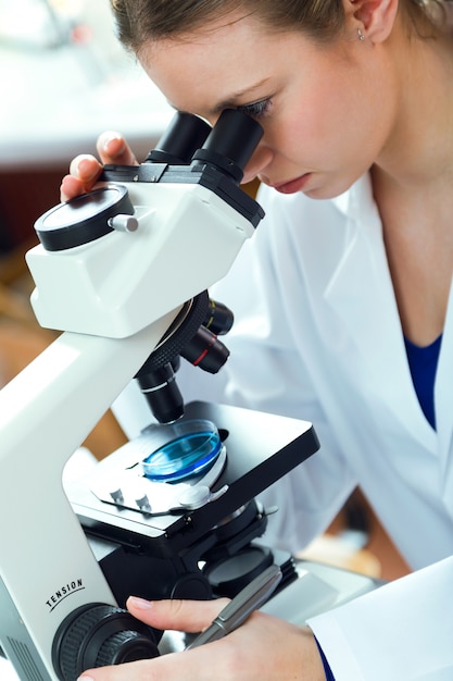 Junge Frau sucht durch Mikroskop im Labor.