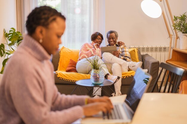 Junge Frau Telearbeit, während sie sich zu Hause um ihre Eltern kümmert Sie genießen Technologie Konzept Familienvereinbarkeit Altenpflege