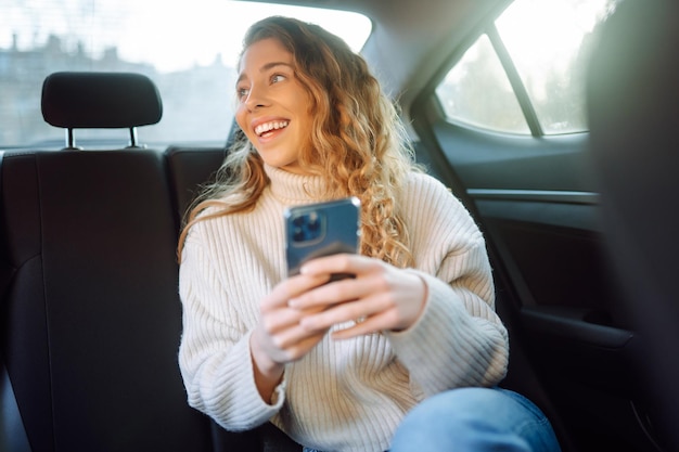 Junge Frau telefoniert auf dem Rücksitz des Autos. Business-Technologie-Blogging-Konzept