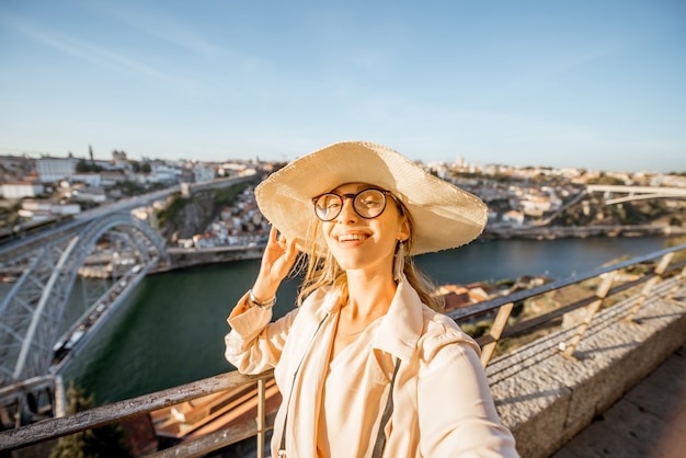 Junge Frau Tourist, die schöne Aussicht auf das Stadtbild aus der Luft mit berühmter Brücke während des Sonnenuntergangs in der Stadt Porto, Portugal, genießt