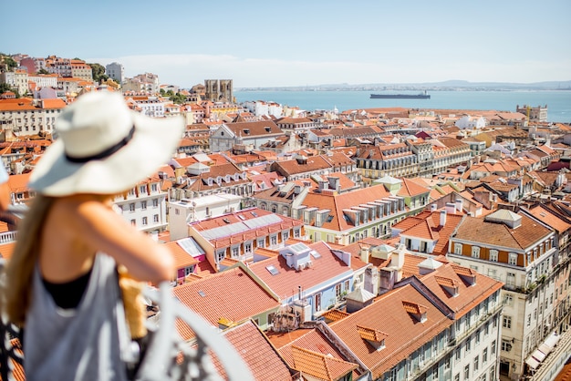 Junge Frau Tourist genießen schöne Stadtbild Draufsicht auf die Altstadt während des sonnigen Tages in Lissabon, Portugal. Bild fokussiert auf den Hintergrund