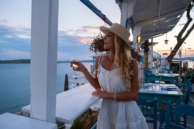 Junge Frau Tourist in Strohhut sitzen im Cliff Café mit Meerblick bei Ermioni Griechenland?