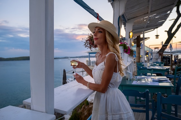 Junge Frau Tourist in Strohhut sitzen im Cliff Café mit Meerblick bei Ermioni Griechenland?