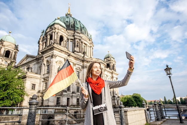 Junge Frau Tourist macht Selfie mit deutscher Flagge vor dem berühmten Dom in Berlin City