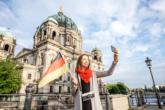 Junge Frau Tourist macht Selfie mit deutscher Flagge vor dem berühmten Dom in Berlin City