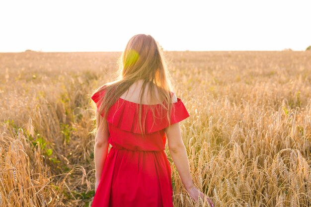 Junge Frau trägt rotes Kleid im Summer Field, Rückansicht