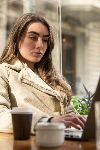 Foto junge frau trägt warme kleidung und benutzt einen laptop