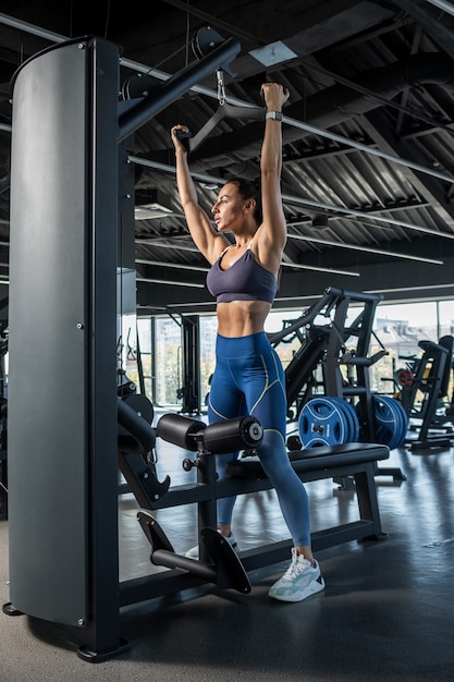 Junge Frau trainiert an Latzugmaschine im Fitnessstudio