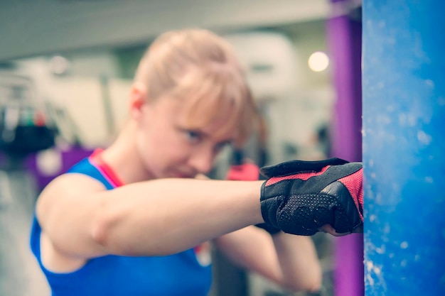 Foto junge frau trainiert boxhandschuhe für boxsack mädchen macht starken kick cross fit training nahkampf frauenkampf ohne regeln körper gesunder lebensstil