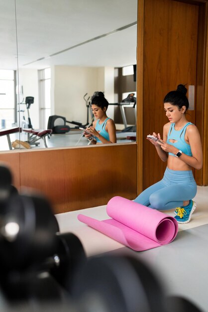 Foto junge frau trainiert im fitnessstudio mit ihrem handy