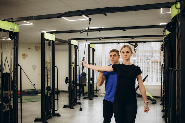 Junge Frau trainiert mit persönlichem Trainer Mann im Fitnessstudio Hochwertiges Foto