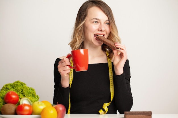 Junge Frau trifft eine Wahl zwischen gesundem und ungesundem Essen.