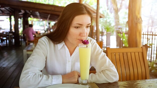 Junge Frau trinkt einen Fruchtcocktail in einem Café.