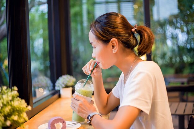 Junge Frau trinkt Glas auf einem Tisch im Restaurant