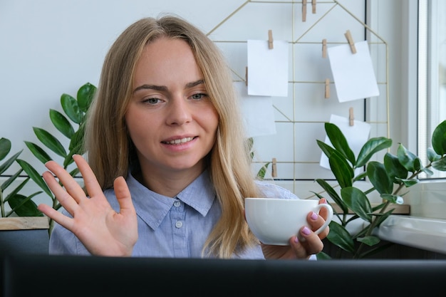 Foto junge frau trinkt kaffee, arbeitet zu hause am computer und berechnet die monatlichen ausgaben für eine hypothek