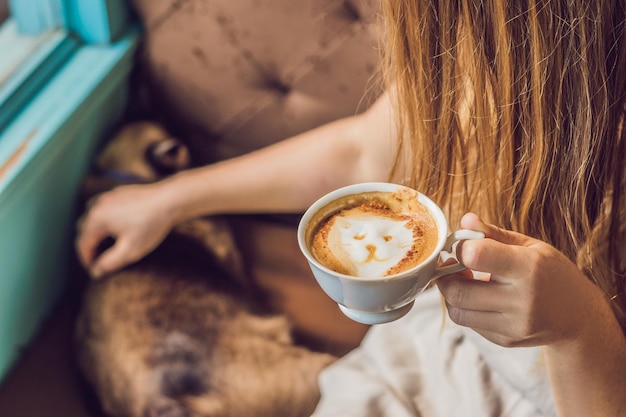 Junge Frau trinkt Kaffee und streichelt die Katze