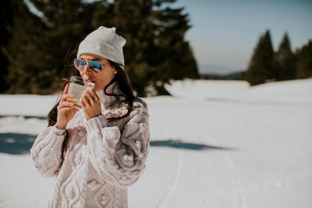 Junge Frau trinkt Limonade auf der Bergskipiste