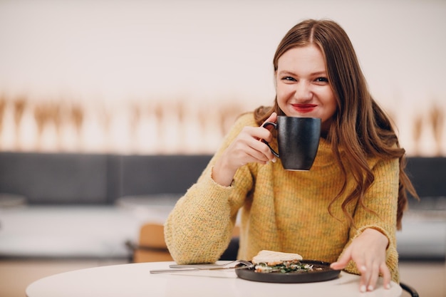 Junge Frau trinkt morgens Kaffee im Café