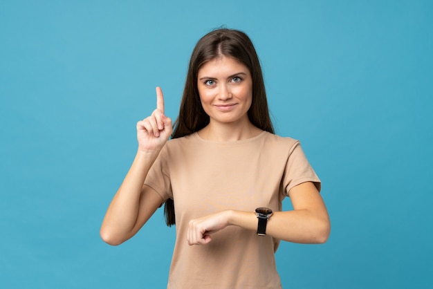 Junge Frau über dem lokalisierten Blau, welches die Handuhr betrachtet