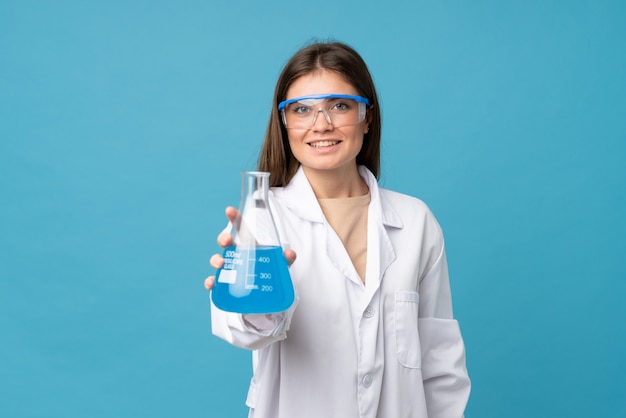 Junge Frau über getrenntem Blau mit einem wissenschaftlichen Reagenzglas