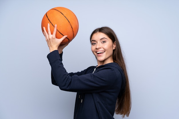 Junge Frau über getrennter blauer Wand mit Kugel des Basketballs