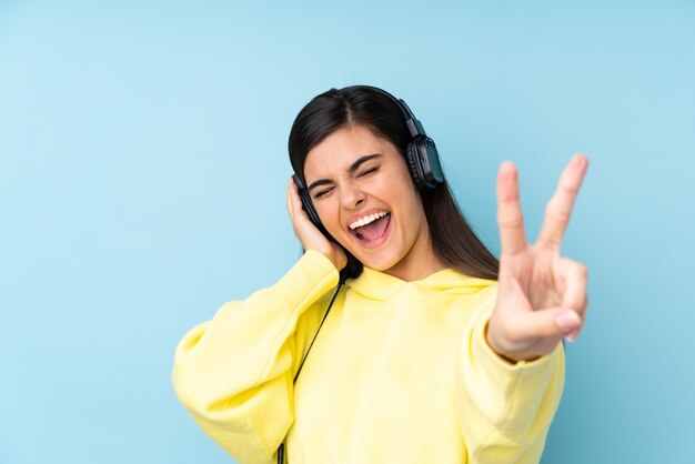 Junge Frau über isolierte blaue hörende Musik und Gesang