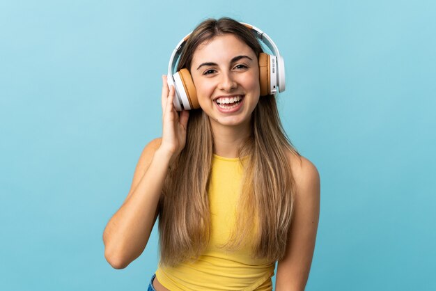 Junge Frau über isolierte blaue Wand, die Musik hört