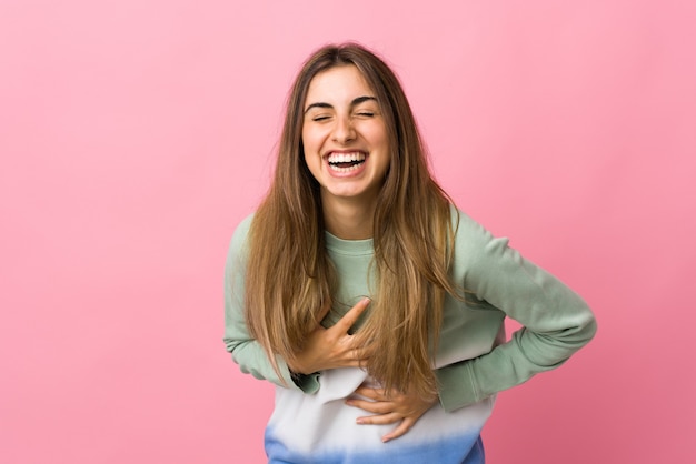 Junge Frau über isolierte rosa Wand, die viel lächelt