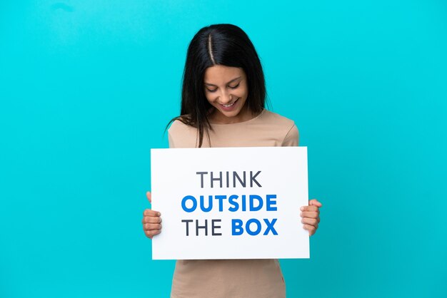 Junge Frau über isoliertem Hintergrund mit einem Plakat mit Text Think Outside The Box