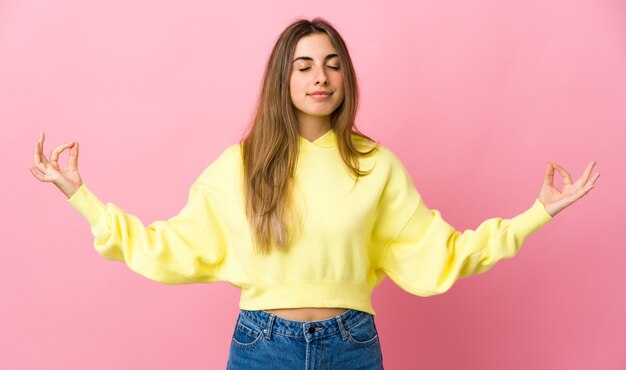 Junge Frau über isoliertem Rosa in Zen-Pose