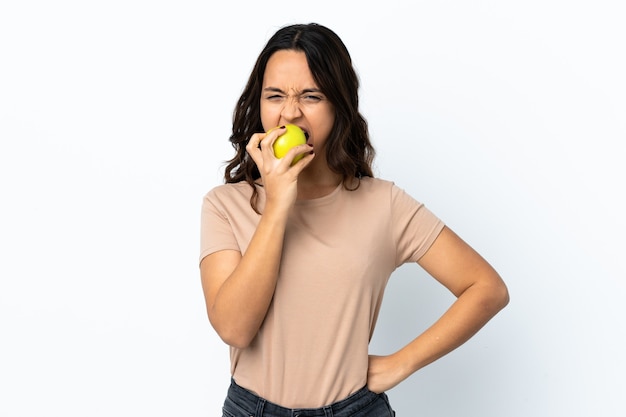 Junge Frau über isoliertem Weiß, das einen Apfel isst