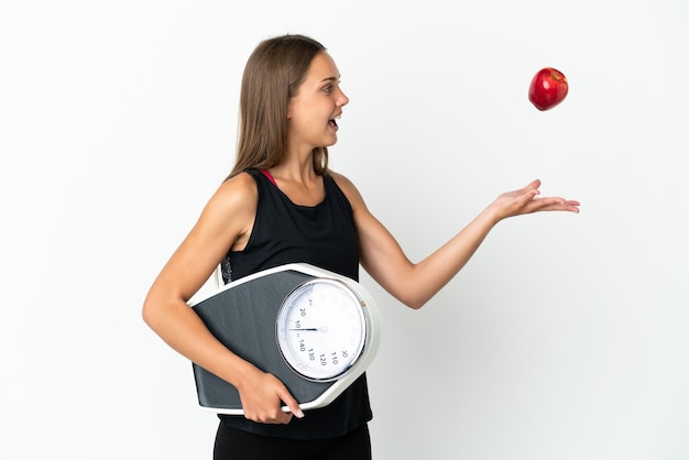 Junge Frau über lokalisiertem weißem Hintergrund mit Waage und mit einem Apfel