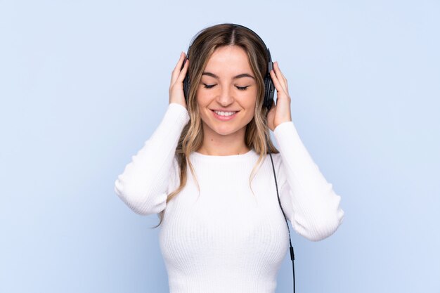 Junge Frau über lokalisierter hörender Musik der blauen Wand