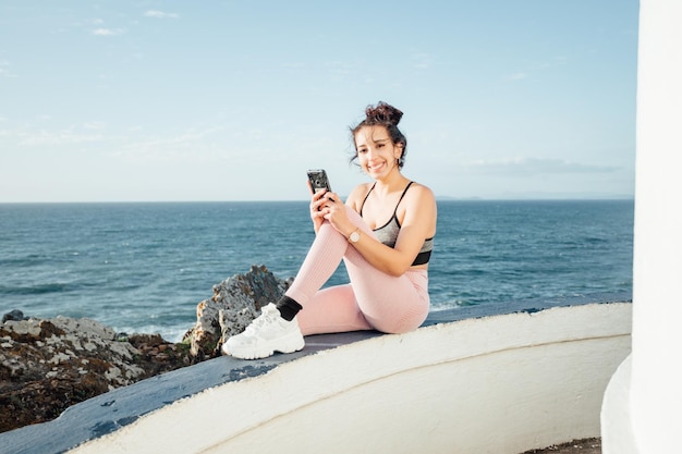 Junge Frau überprüft ihr Telefon nach einem Trainingstag im Freien Überprüfen Sie die sozialen Medien und veröffentlichen Sie neue Bilder für ihre Fans Berühmte Sportler und Body Summer gut aussehendes Konzept