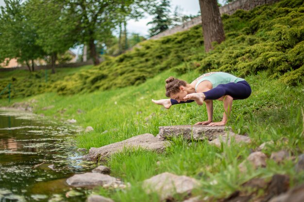 Junge Frau übt Yoga nahe einem Fluss