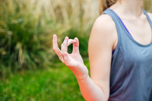 Junge Frau übt Yoga und meditiert im Lotussitz im Park