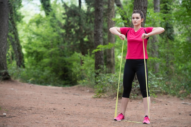 Junge Frau Übung mit Widerstandsband in bewaldeten Waldgebiet Fitness gesunder Lebensstil Konzept