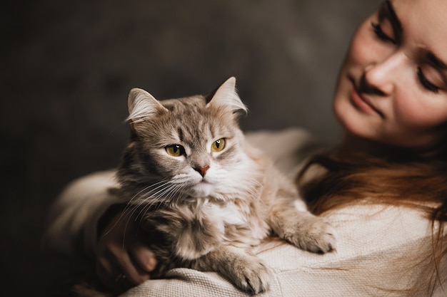 Junge Frau umarmt eine graue flauschige Katze