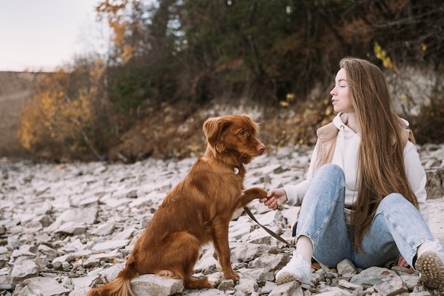 Junge Frau und Hund Retriever Spaziergänge am Flussufer in der Herbstsaison